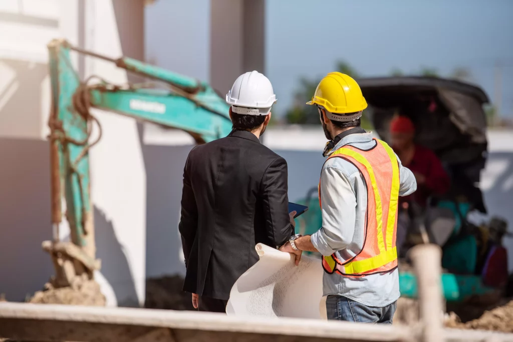 Engenheiro e operário analisando o andamento de uma obra